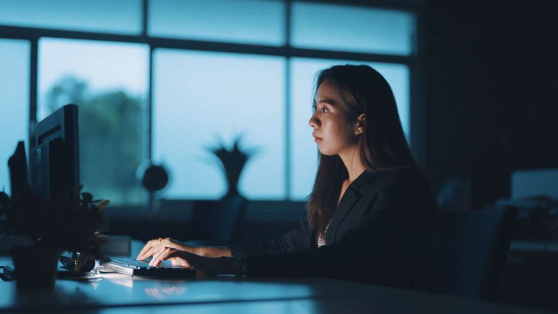 Women sitting in a dark room while typing on a computer.