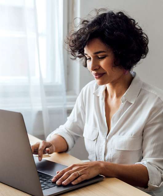 Woman sitting at table and typing on a laptop.