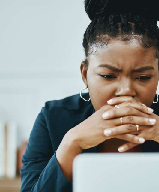 Woman with hands over mouth staring at a computer