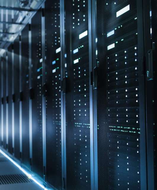 Person standing at the end of a hallway of computer servers.